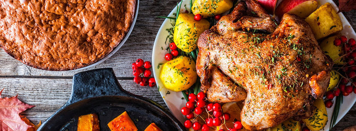 A Thanksgiving dinner spread with roasted pumpkin, pie, soup, and a roasted turkey on a bed of candied lemon slices and apples