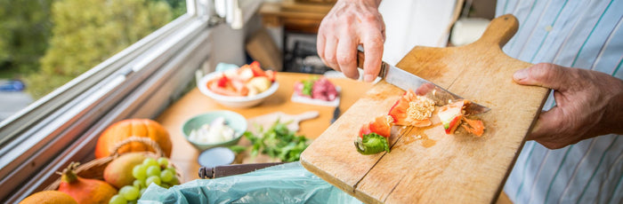 A person throwing away chopped vegetable residue into the trash bin