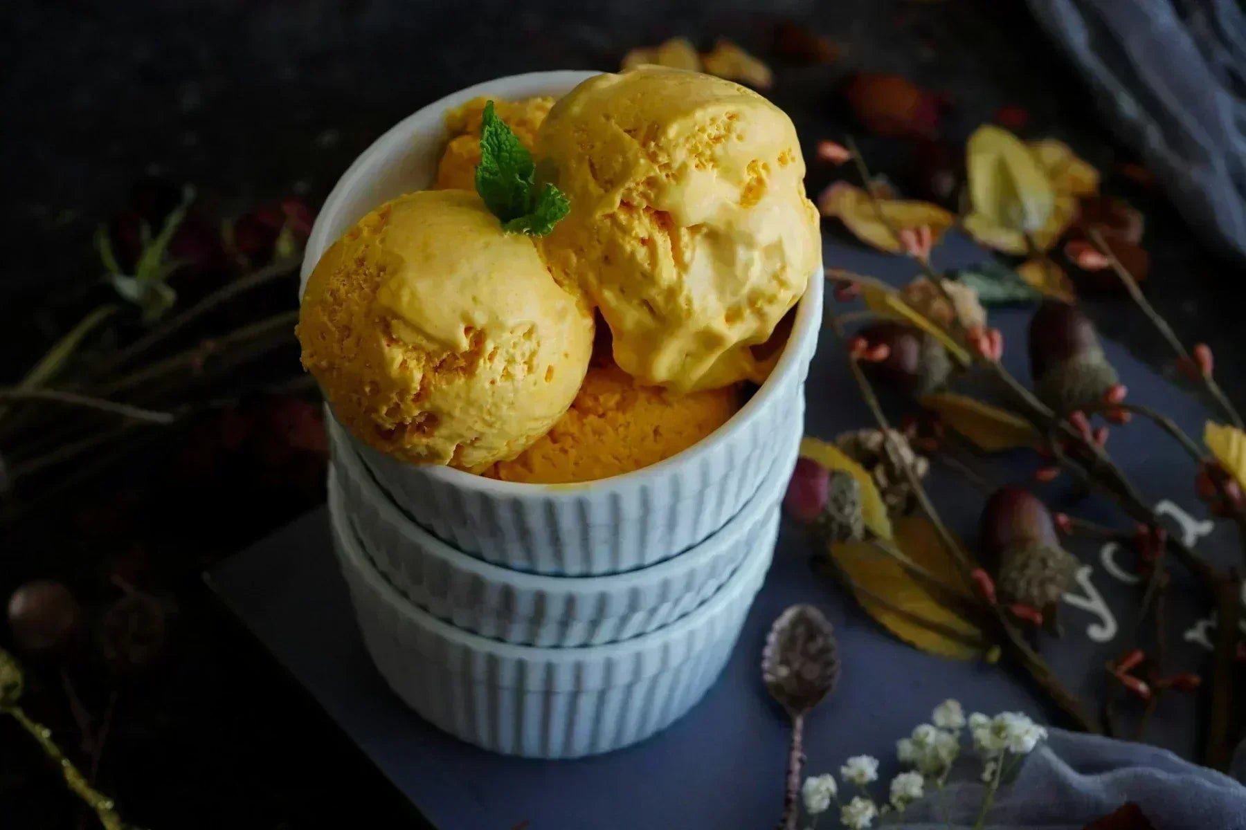Scoops of mango ice cream with a mint leaf in a stack of bowls