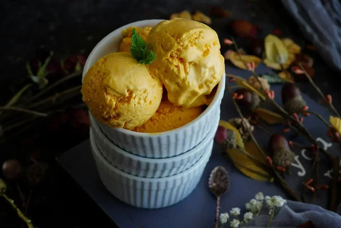 Scoops of mango ice cream with a mint leaf in a stack of bowls