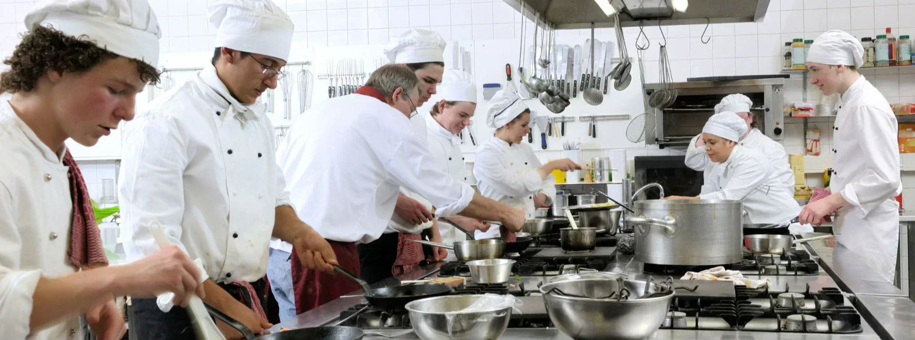 Chefs dressed in traditional outfits cooking food in a busy restaurant kitchen