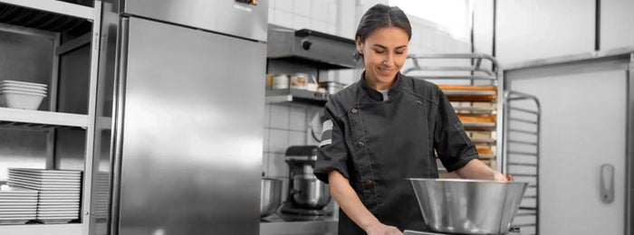 A young woman, smiling, works in a small commercial kitchen