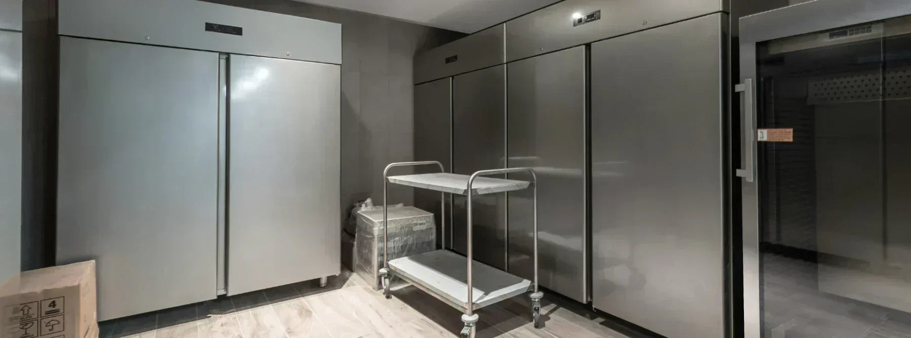 A spacious professional kitchen area features stainless steel refrigerators arranged neatly against the walls