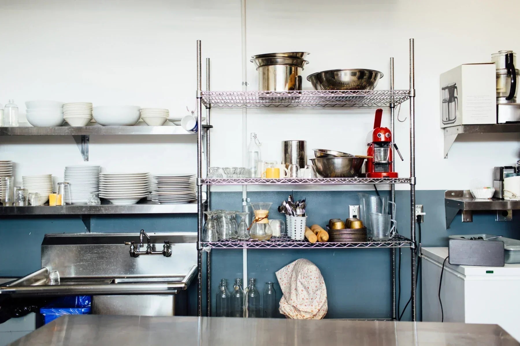 Various kitchenware items are neatly organized on metal shelves in a commercial kitchen.