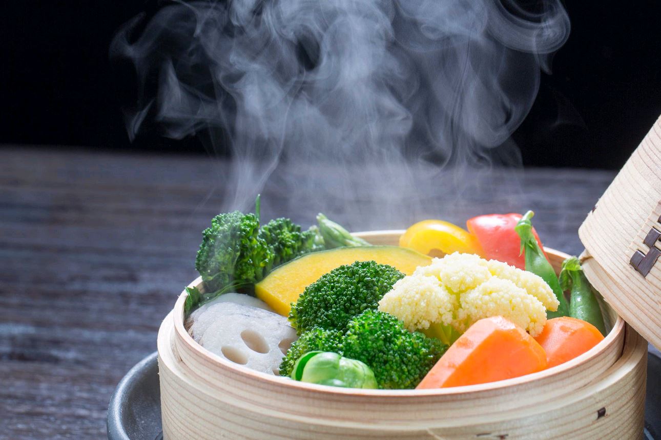 Steaming Vegetables in Bamboo Steamer on dark background