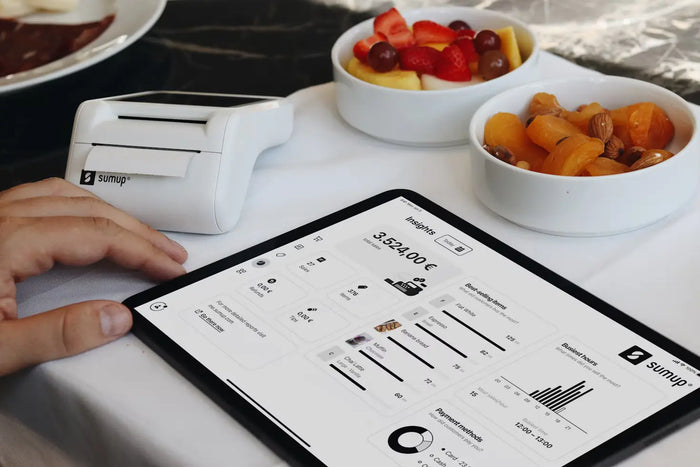 A tablet, placed next to bowls and card reader displays restaurant data.
