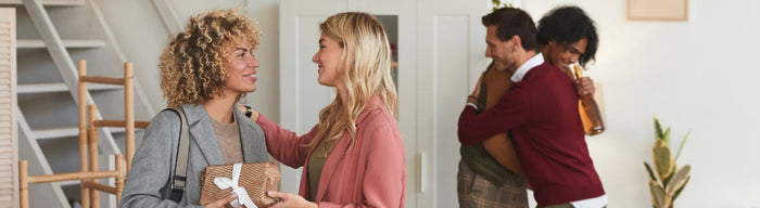 A couple greets their friends at a housewarming party