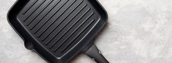 A cast iron skillet and a kitchen towel on a wooden table 