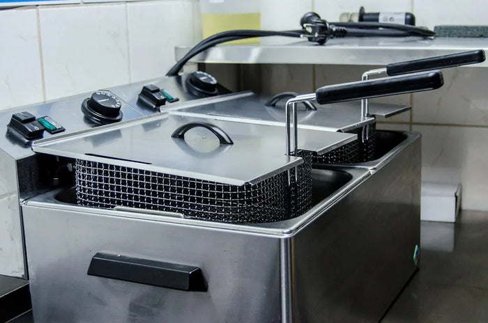 An unplugged silver deep fryer unit sits on a kitchen countertop. 