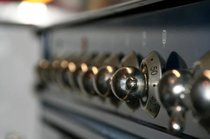An extreme close up shows dials on a kitchen oven. 