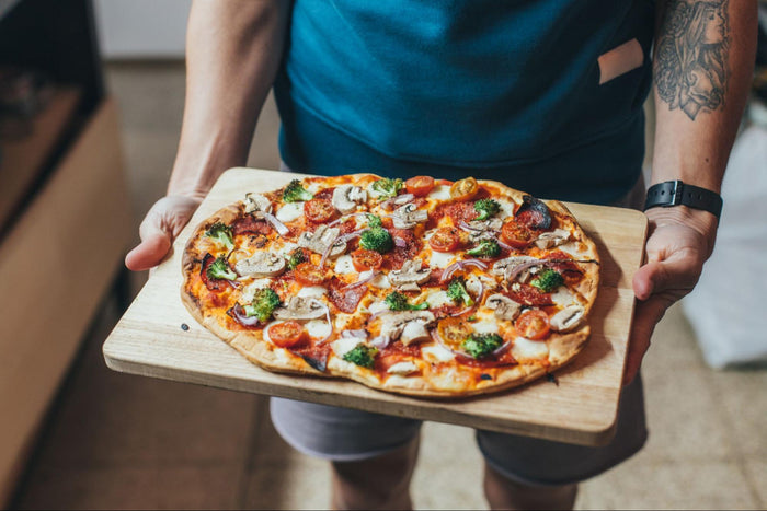 Cropped image of a man holding homemade pizza