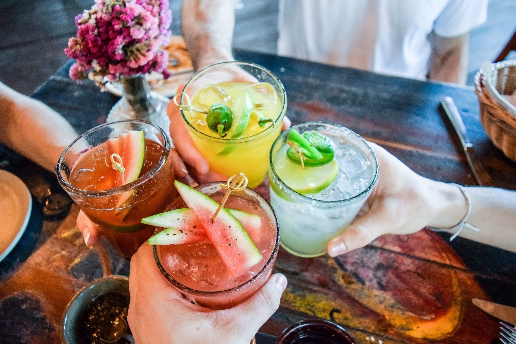 Four people toasting their drinks over a dining table 