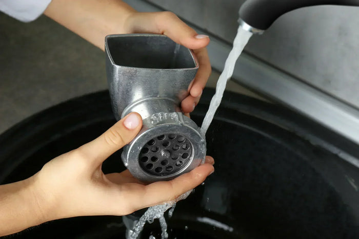 Close-up of a person cleaning manual meat grinder