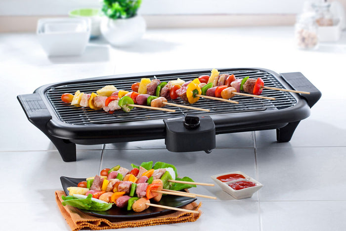A group of kebab sticks lying on top of a smokeless grill