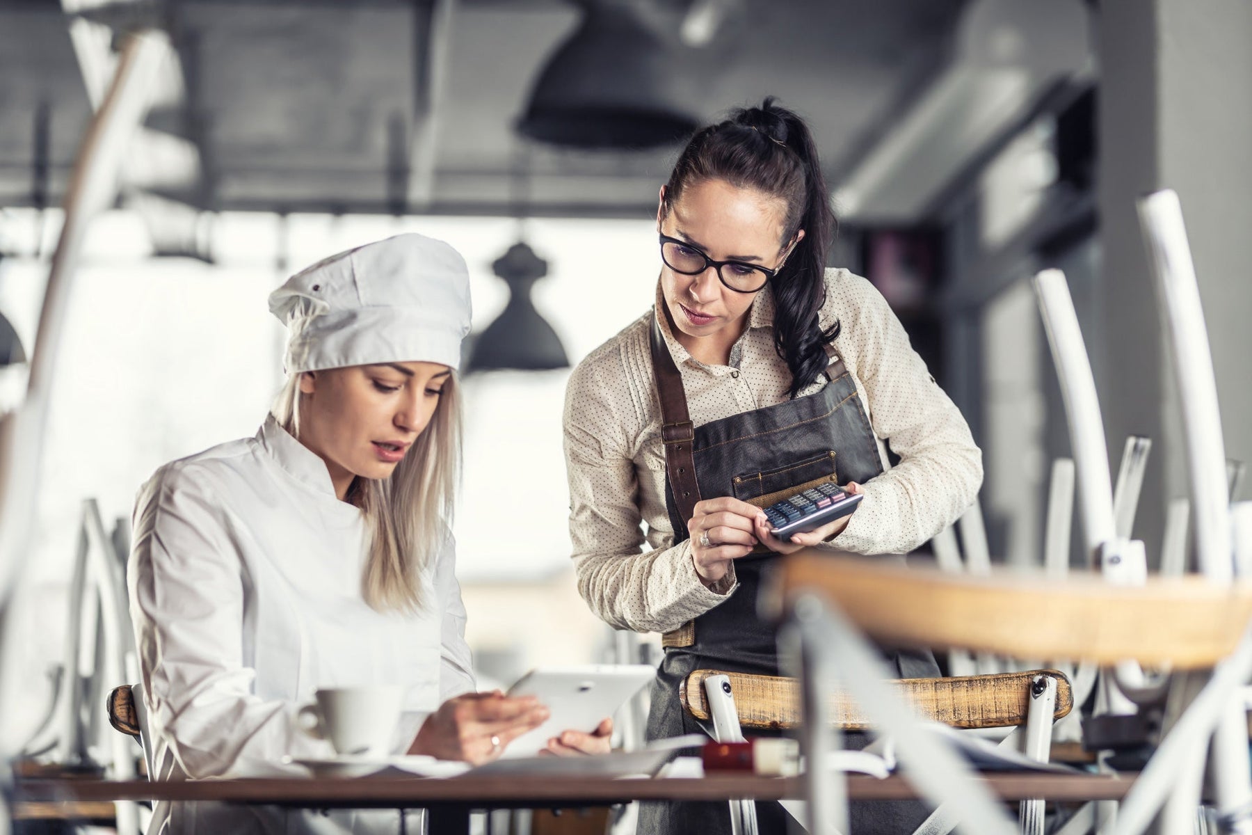 Chef and waitress holding a tablet and calculator respectively