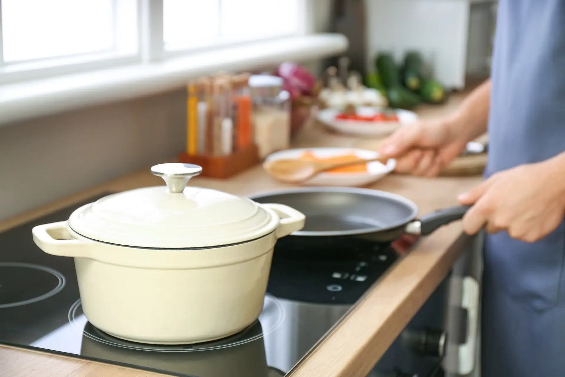 A home cook using two different types of pots and pans, including a sauté pan and Dutch oven