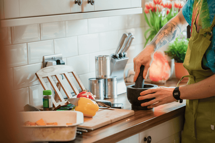 A home cook uses a granite stone mortar and pestle while preparing a meal