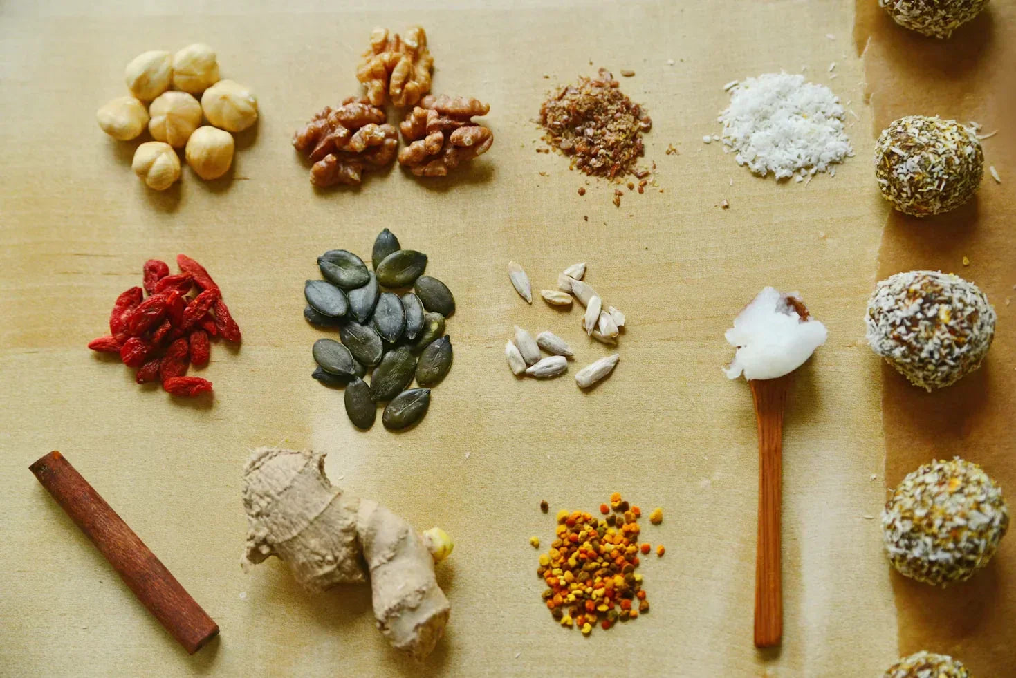 Sixteen spices (of various types) are evenly displayed on a well-light wooden surface. 