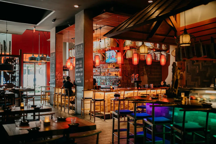 Restaurant interior with wooden tables, Asian-signage, and soft orange and yellow lighting. 